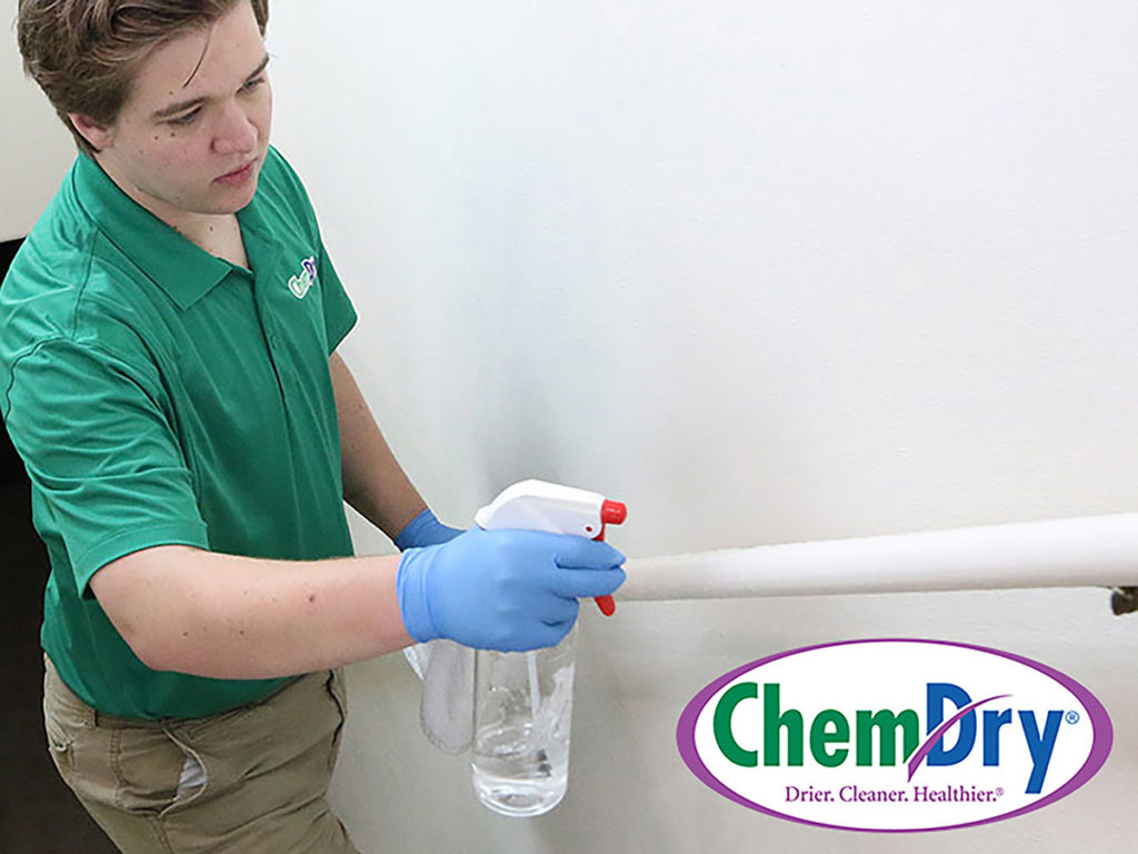 Chem-Dry cleaning franchise employee sanitizes handrail